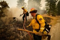 Tim Lesmeister, right, and Rick Archuleta, of the Clovis Fire Department, put out hot spots left behind by the Creek Fire in Tollhouse, Calif., Sept. 8, 2020.