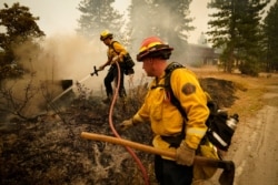 FILE - Tim Lesmeister, right, and Rick Archuleta, of the Clovis Fire Department, put out hotspots left behind by the Creek Fire, in Tollhouse, Calif., Sept. 8, 2020.