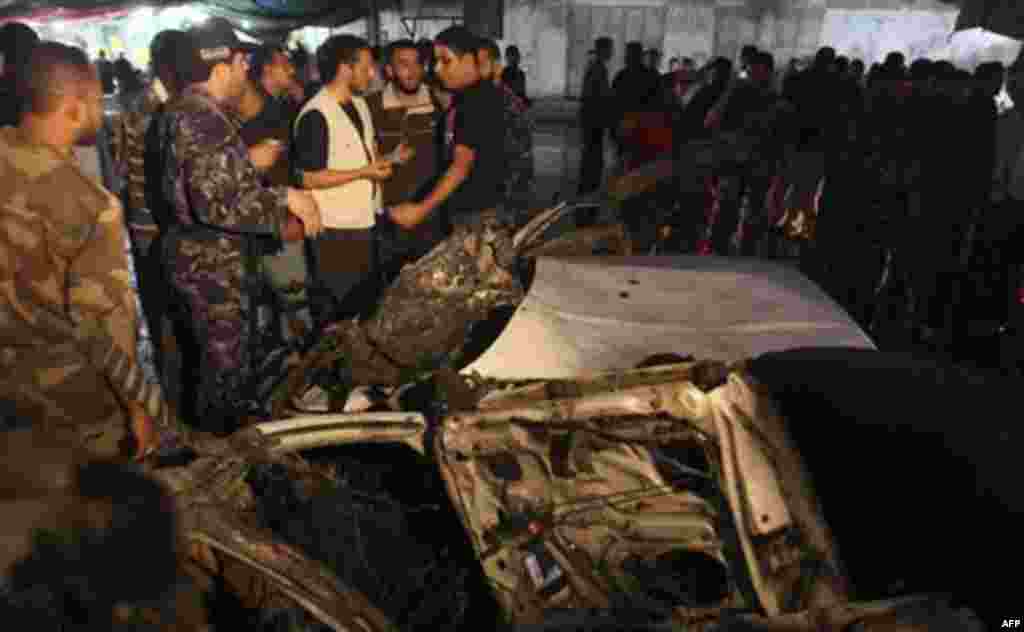 Palestinians gather around a destroyed car after an explosion in Gaza City, Wednesday, Nov. 17, 2010. Hamas officials say one person has been killed and four others wounded in a car explosion in the Gaza Strip. Hamas media reported the car was hit in an a