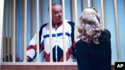 FILE - Sergei Skripal is seen behind bars on a screen of a monitor outside a courtroom in Moscow, Aug. 9, 2006.