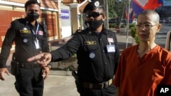 FILE - Court securities direct Cambodian-American lawyer Theary Seng, right, dressed in a prison-style orange outfit, to the entrance of Phnom Penh Municipal Court in Phnom Penh, Cambodia, Tuesday, Jan. 4, 2022.