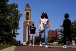 FILE - Masked students walk through the campus of Ball State University in Muncie, Indiana, Sept. 10, 2020. College towns across the U.S. have emerged as coronavirus hot spots in recent weeks.