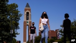 Masked students walk through the campus of Ball State University in Muncie, Ind., Sept. 10, 2020, as schools struggle to contain the virus. Out of nearly 600 students tested for the virus there, more than half have returned been found positive. 