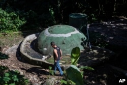 Otavio Alves Barros walks by the sewage treatment Biosystem of the Enchanted Valley community on the outside of Tijuca National Forest in Rio de Janeiro, Brazil on June 6, 2022. (AP Photo/Bruna Prado)