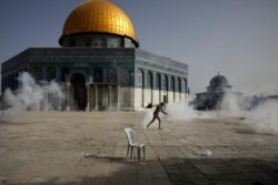FILE - A Palestinian man runs away from tear gas during clashes with Israeli security forces in front of the Dome of the Rock Mosque at the Al-Aqsa mosque compound in Jerusalem's Old City, May 10, 2021.