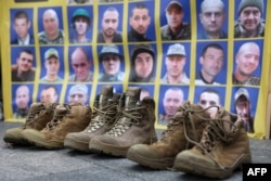 Soldiers' boots sit in front of a poster with portraits of missing Ukrainian servicemen at Independence Square in Kyiv on Oct. 16, 2024. Relatives of the missing held a rally to demand that Ukrainian authorities speed up the search for their loved ones.