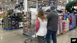 FILE - Shoppers pass displays of goods in a Costco warehouse, Feb. 25, 2024, in Sheridan, Colo. The Trump administration will implement 25% tariffs on Mexican and Canadian goods and a 10% tariff on all Chinese imports on Feb. 1, 2025.