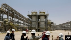 Para insinyur perusahaan minyak asal Arab Saudi, Aramco, dan awak media tampak mengamati area pabrik Hawiyah Natural Gas Liquids dalam satu kunjungan di Hawiyah, pada 28 Juni 2021. (Foto: AP/Amr Nabil)