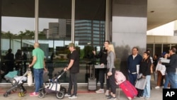 Marni Larsen y su hijo, Damon Rasmussen de Holladay, Utah, hacen fila con la esperanza de obtener el pasaporte de su hijo afuera de la Agencia de Pasaportes de Los Ángeles el 14 de junio de 2023