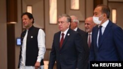 Pakistan's Prime Minister Imran Khan, left, Uzbekistan's President Shavkat Mirziyoyev, center, and Afghanistan's President Ashraf Ghani, behind Mirziyoyev, walk to attend a Central-South Asia trade summit in Tashkent, Uzbekistan, July 16, 2021.