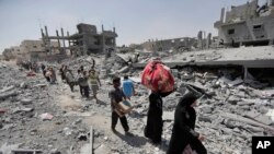 Warga Palestina membawa harta benda mereka dari rumah mereka yang hancur akibat bom di kota Beit Hanoun, Jalur Gaza, dekat dengan perbatasan Israel, Jumat 1 Agustus 2014.