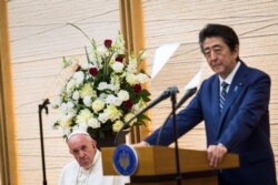 Japan's Prime Minister Shinzo Abe, right, delivers a speech as Pope Francis listens in Tokyo, Nov. 25, 2019.