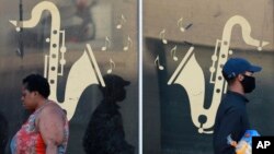 People walk past the window of a live jazz bar which has been closed during lockdown in Cape Town, South Africa, on May 13, 2020. 