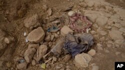 FILE - Human remains lie on the ground in a ravine near Badoush, northern Iraq, Sept. 6, 2017. Iraqi military investigators have identified two mass graves in the area they say contain the remains of at least 500 people, executed by Islamic State militants.