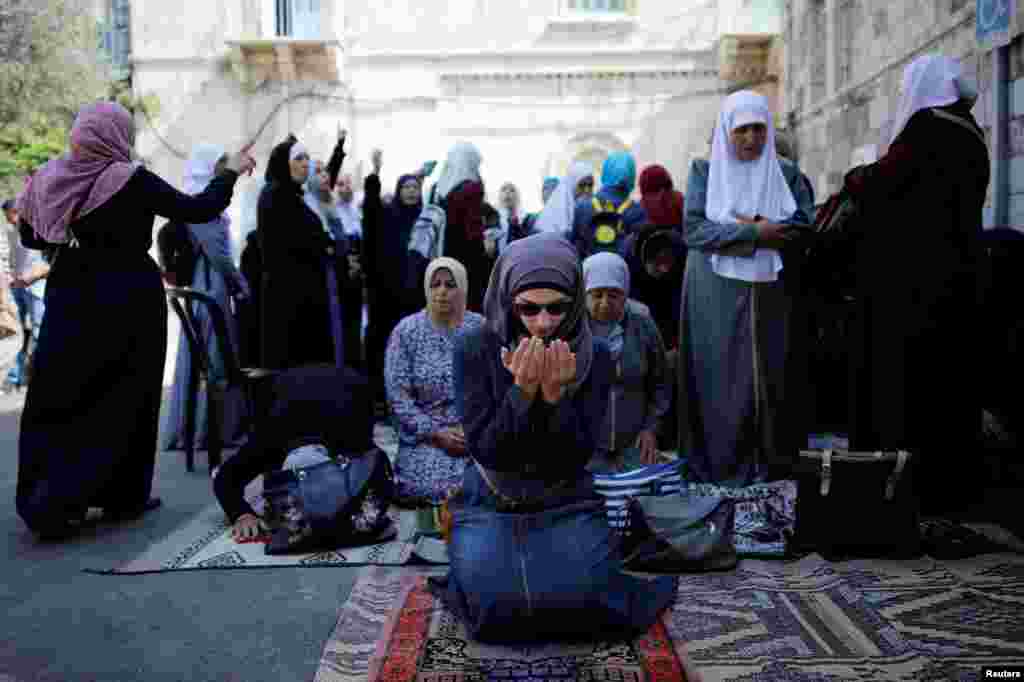 Palestinian women pray as others shout slogans outside the compound known to Muslims as Noble Sanctuary and to Jews as Temple Mount, in Jerusalem&#39;s Old City.
