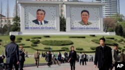 People walk beneath portraits of late leaders, Kim Il Sung, left, and Kim Jong Il, in Pyongyang, North Korea, April 18, 2017.