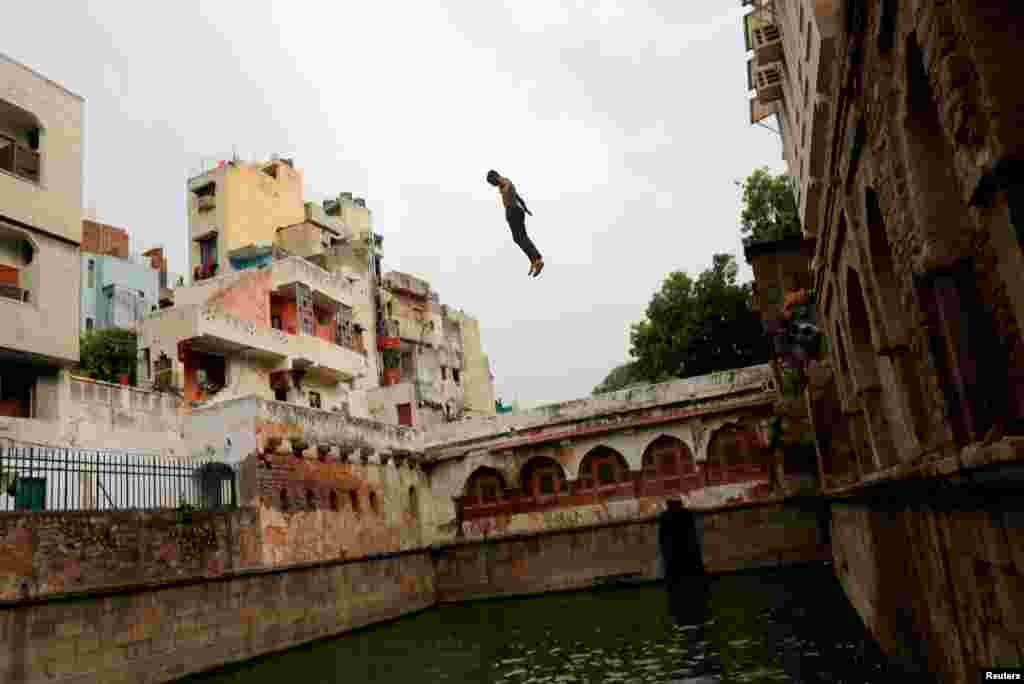 A boy jumps into a stepwell, built inside the shrine of Sufi Saint Nizamuddin Auliya, to cool off on a hot summer day in New Delhi, India.