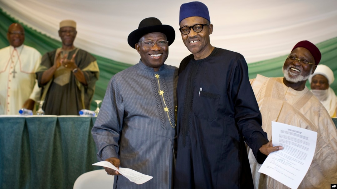 FILE - Nigeria's President Goodluck Jonathan, center-left, and opposition candidate Gen. Muhammadu Buhari, center-right, hug and shake hands after signing a renewal of their pledge to hold peaceful "free, fair, and credible" elections, at a hotel in the capital Abuja, March 26, 2015. 