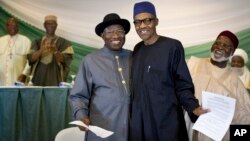 FILE - Nigeria's President Goodluck Jonathan, center-left, and opposition candidate Gen. Muhammadu Buhari, center-right, hug and shake hands after signing a renewal of their pledge to hold peaceful "free, fair, and credible" elections, at a hotel in the capital Abuja, March 26, 2015. 