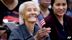 Hong Inh waves an American flag and smiles after taking the oath to become a United States citizen at the Los Angeles Convention Center, in Los Angeles, California, Aug. 22, 2017.