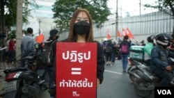 Baifern Benjama, a pro-democracy protester, holds a sign reading "Reform = make it better," at a Bangkok street protest. (Vijitra Duangdee/VOA)