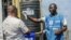 Un homme se lave les mains au chlore alors qu'un agent de santé vérifie sa température à Goma en RDC le 15 juillet 2019.