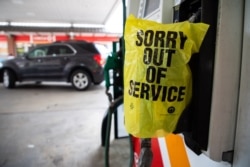 FILE - An "Out of Service" bag covers a gas pump as cars line up at a Circle K gas station near uptown Charlotte, North Carolina, May 11, 2021, after a ransomware attack shut the Colonial Pipeline, a major East Coast gasoline provider.