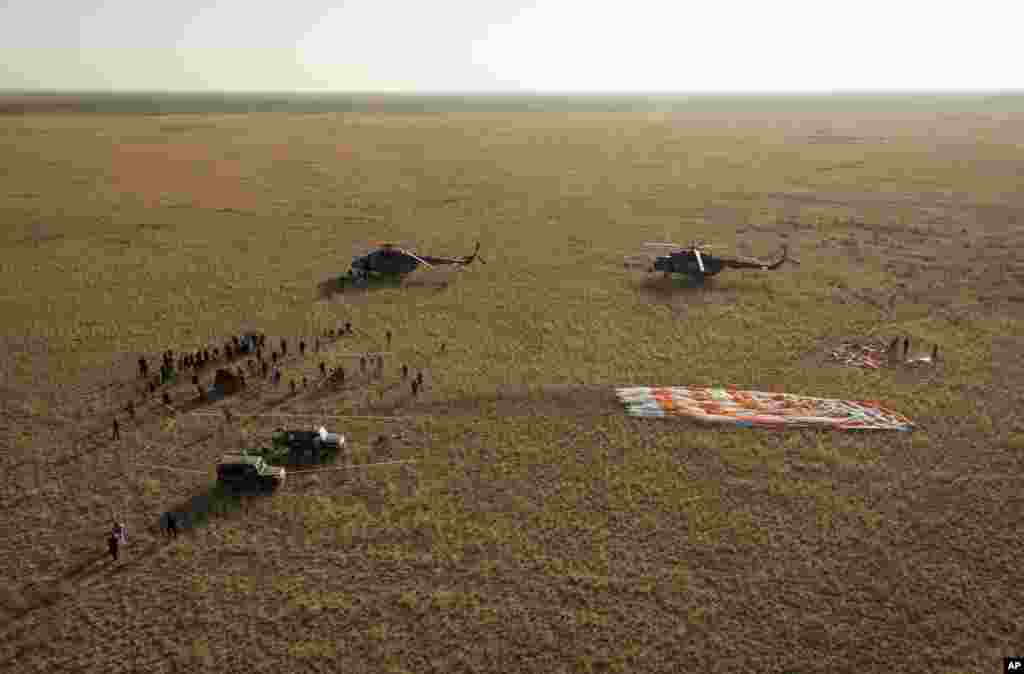 Ground support personnel stand at the landing site after the Soyuz TMA-12M spacecraft landed near the town of Zhezkazgan, Kazakhstan, Sept. 11, 2014.