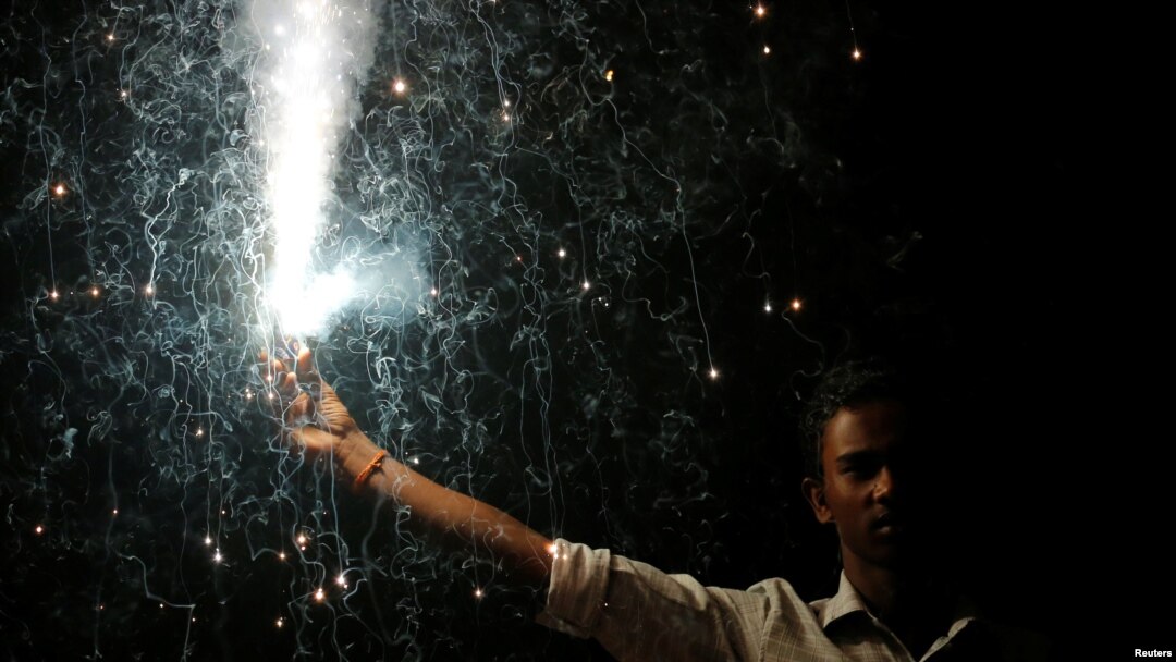 Seorang pria memegang petasan saat perayaan Hindu, Festival Diwali, atau festivla cahaya di Mumbai, India, 19 Oktober 2017.