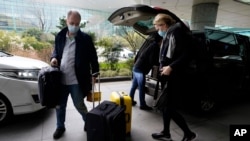 FILE - John Watson and Thea Koelsen Fischer of the World Health Organization team arrive at the VIP terminal of the airport to leave at the end of the WHO mission in Wuhan, China, Feb. 10, 2021. 