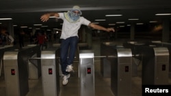 A protester jumps over a subway turnstile during a protest demanding improvements be made to the public transport system, at the bus station in the centre of Brasilia, June 19, 2013. 