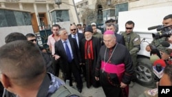 Iraqi Christian lawmaker, Younadem Kana, center left, Iraq's top Catholic prelate, Chaldean Cardinal Emmanuel III Delly, center, and Bishop Shlimone Wardoni, center right, are seen outside Our Lady of Deliverance church the morning after its congregation 