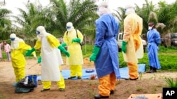 Des agents de la santé, vêtus d’équipement de protection contre le virus Ebola, transportent sur une civière un enfant nouveau-né mort, à Dubreka en Guinée, le 19 juin 2015. (AP Photo/Youssouf Bah)