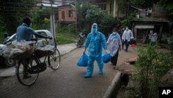 A health worker walks during a door-to-door drive to take nasal swab samples to test for COVID-19 in Gauhati, India, Aug. 29, 2020.