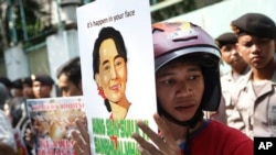 Une militante montre un poster avec le portrait d'Aung San Suu Kyi lors d'une manifestation qui demande la fin des violences contre les Rohingyas dans l'État de Rakhine, à Jakarta, Indonésie, le 29 mai 2015.