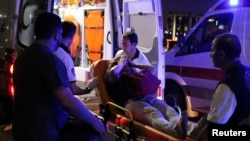 An injured woman covers her face as she is carried by paramedics into ambulance at Istanbul Ataturk Airport, Turkey, following explosions at the facility, June 28, 2016. 