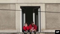 FILE - A couple in governent-mandated self-isolation are seen in their apartment window in downtown Warsaw, Poland, March 22, 2020.