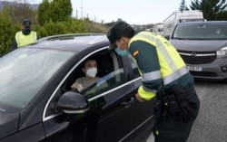 A Spanish Civil Guard questions a motorist after the Navarran local government limited all non-essential movement in and out of the region for two weeks starting Thursday, amid the coronavirus outbreak, Ziordia, Spain, Oct. 22, 2020. (Reuters)