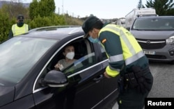 A Spanish Civil Guard questions a motorist after the Navarran local government limited all non-essential movement in and out of the region for two weeks starting Thursday, amid the coronavirus outbreak, Ziordia, Spain, Oct. 22, 2020. (Reuters)