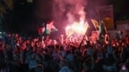 Protesters lift Palestinian flags and a portrait of Mohammed Deif chief of Al-Qassam Brigades, Hamas' military wing, during a rally at the entrance of the French embassy complex in Beirut early on Oct. 18, 2023.