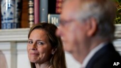 Supreme Court nominee Judge Amy Coney Barrett looks over to Senate Majority Leader Mitch McConnell of Kentucky as they meet with on Capitol Hill in Washington, Sept. 29, 2020. 