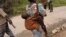 Une jeune femme combattant avec le bataillon Mai Mai à Irangi, dans le district de Bunyakiri au Sud-Kivu en RDCongo, porte son fusil et son fils le 14 janvier 2004.