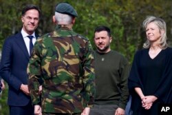 Belakang dari kiri, Perdana Menteri Belanda Mark Rutte, Presiden Ukraina Volodymyr Zelenskiy dan Kajsa Ollongren, Menteri Pertahanan Belanda berdiri di depan seorang prajurit selama kunjungan di pangkalan udara militer di Soesterberg, Belanda, 4 Mei 2023. (Yves Herman/Pool via AP)