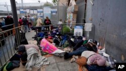 Para migran menunggu untuk mengajukan suaka di dekat pintu masuk Pelabuhan San Isidro, yang menghubungkan kota Tijuana, Meksiko dengan San Diego, California, AS.