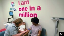 Kenneth Parker Ulrich, left, a research technician at the University of Pittsburgh Medical Center, prepares to collect a blood sample from Erricka Hager, a participant in the "All of Us" research program in Pittsburgh, Aug. 7, 2017.