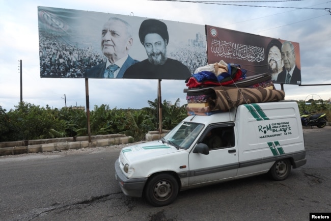 Un vehículo con pertenencias pasa junto a una imagen del presidente del Parlamento libanés, Nabih Berri, y del imán Musa al-Sadr, en Tiro, después de que entrara en vigor el miércoles 27 de noviembre de 2024 un alto el fuego entre Israel y el grupo Hezbolá.