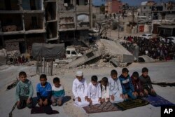 Warga Palestina salat di depan masjid yang hancur akibat serangan udara Israel di Rafah, Jalur Gaza, Jumat, 8 Maret 2024, jelang bulan suci Ramadhan. (Foto: AP)