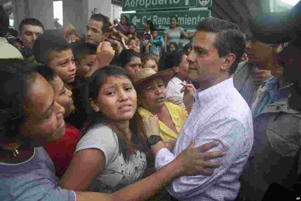 In this photo released by Mexico&#39;s presidential press office, Mexican President Enrique Pena Nieto meets with people affected by Tropical Storm Manuel in the Pacific coast city of Acapulco, Mexico, Sept. 16, 2013.