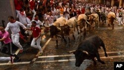 Participantes en el encierro de toros de San Fermín, huyen de un toro de la hacienda José Escolar y de un novillo en el segundo día del famoso festival en Pamplona, España. 