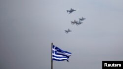Bendera nasional Yunani berkibar sementara pesawat jet tempur terbang dalam formasi di atas Atena, Yunani, 4 April 2017. 